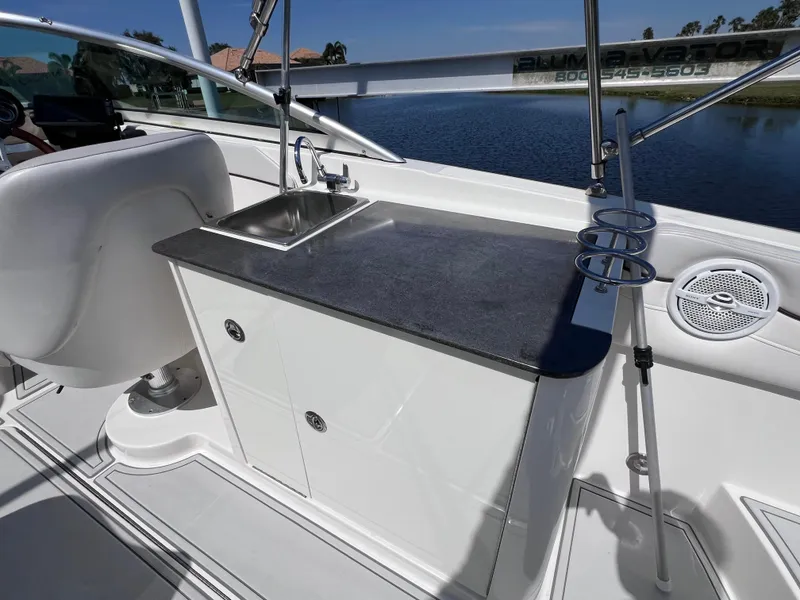 Slide: The Image of 2012 Sea Ray 280 Sundeck boat interior with sink and storage, near a serene lake. - 30