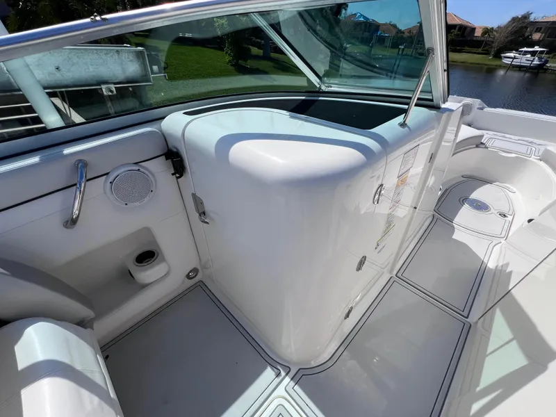 Slide: The Image of 2012 Sea Ray 280 Sundeck interior with seating and storage, docked by a scenic waterfront. - 45