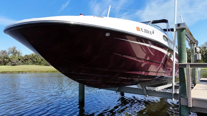 Slide: The Image of 2012 Sea Ray 280 Sundeck boat on lift, docked by a serene waterway. - 8