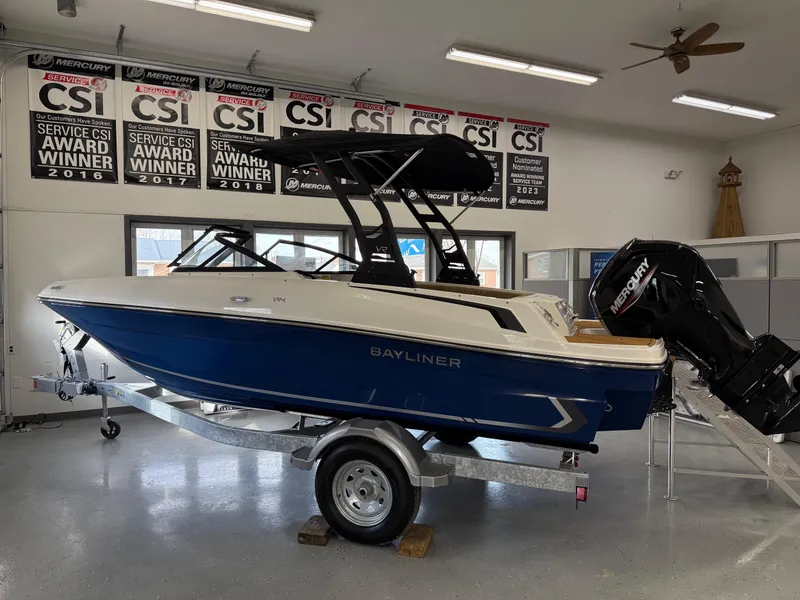 The Image of 2025 Bayliner VR4 Bowrider OB on trailer in showroom, award banners displayed above. - 1