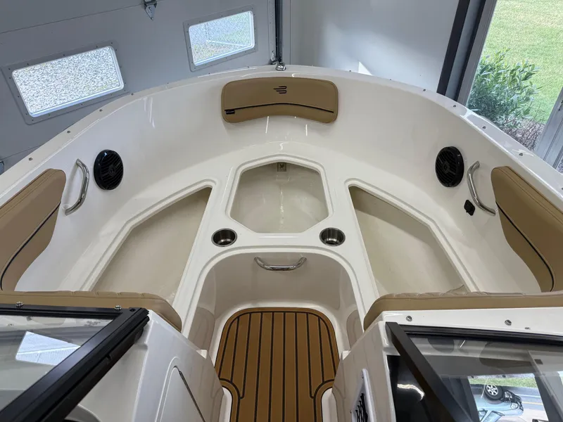 Slide: The Image of 2025 Bayliner VR4 Bowrider OB interior with tan seating and wood accents in a garage setting. - 11