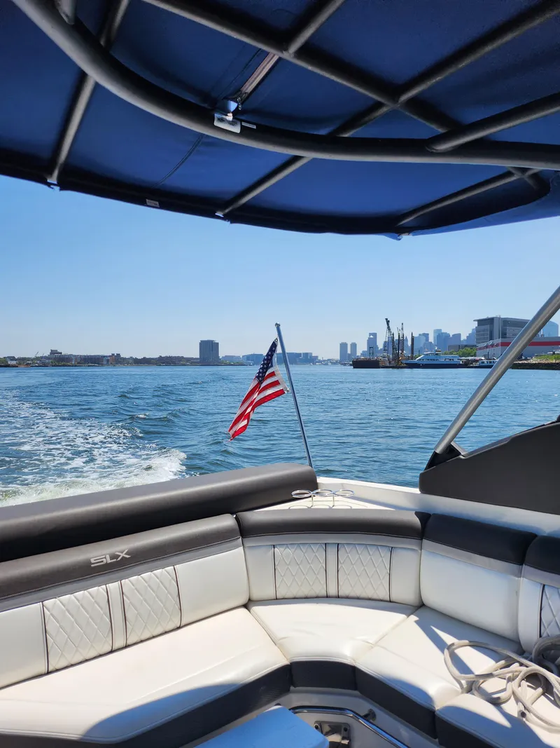 Slide: The Image of 2016 Sea Ray 280 SLX boat cruising with American flag, city skyline in background. - 23
