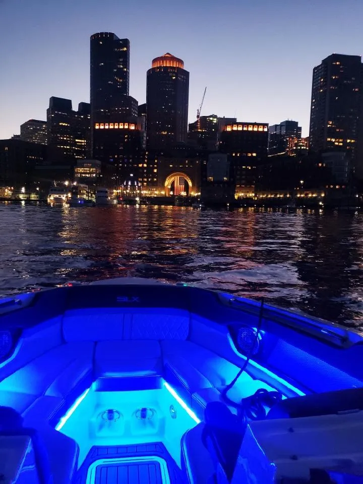 Slide: The Image of Sea Ray 280 SLX 2016 boat with blue interior lights, city skyline at dusk. - 37