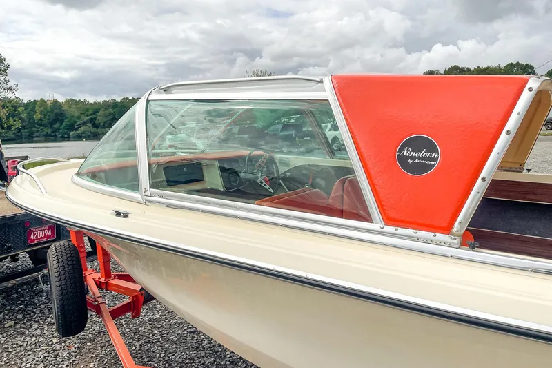 Slide: The Image of 1975 AristoCraft 19 boat with orange accents on a trailer by a lake. - 9