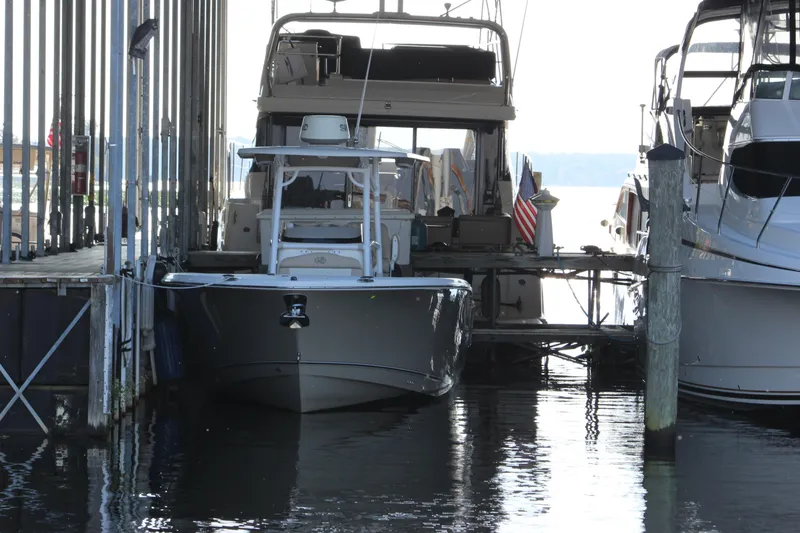 Slide: The Image of 2018 NauticStar 28 XS Offshore boat docked between larger vessels. - 19