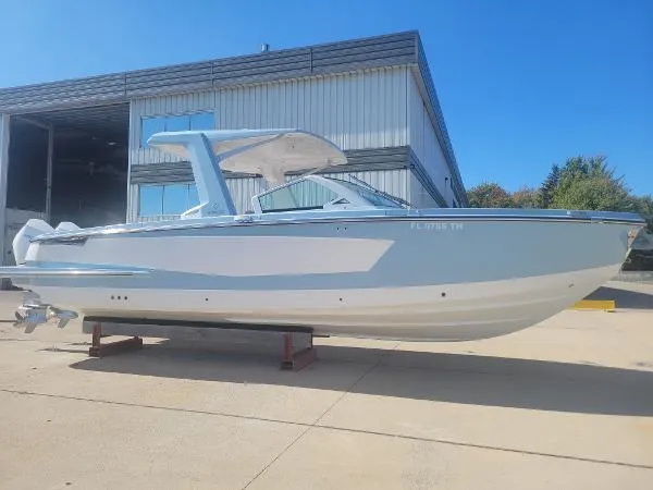 The Image of 2022 Aviara AV32 OB boat displayed outdoors near a warehouse. - 1