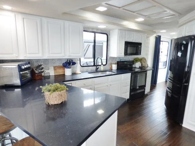 Slide: The Image of Modern kitchen in 1997 Sumerset 16x80 houseboat with sleek black countertops and white cabinetry. - 4