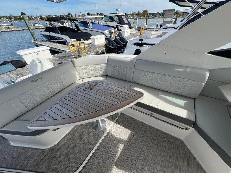 Slide: The Image of 2022 Sea Ray Sundancer 320 OB yacht interior with elegant seating and wooden table at marina. - 15