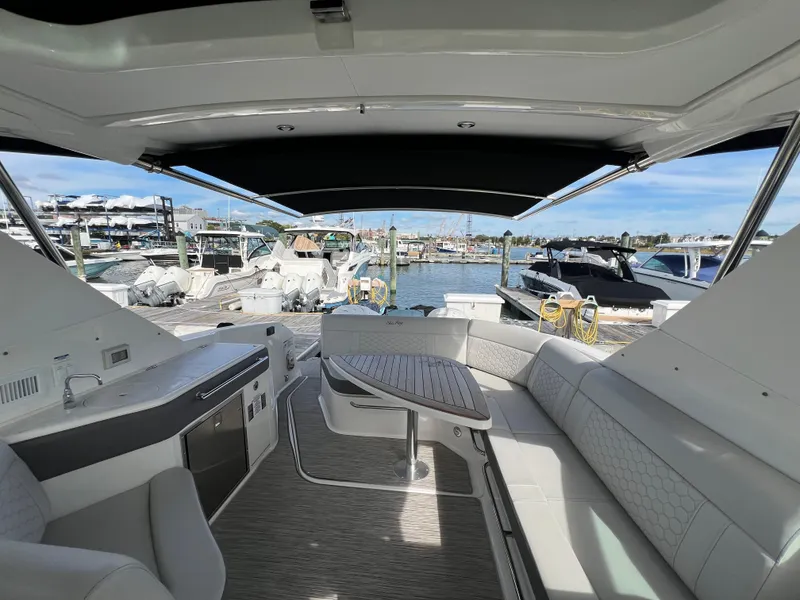 Slide: The Image of 2022 Sea Ray Sundancer 320 OB interior with seating and table, docked at marina. - 22