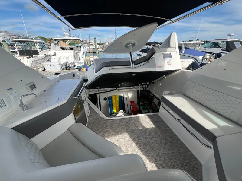 Slide: The Image of 2022 Sea Ray Sundancer 320 OB interior with open storage, seating, and marina view. - 24