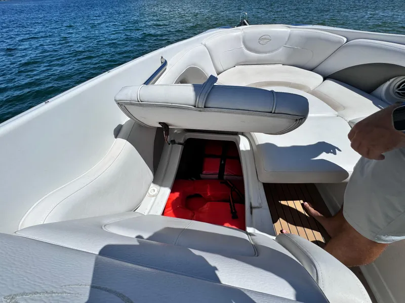 Slide: The Image of 2008 Crownline 300 LS boat interior with open storage compartment, white seating, and lake view. - 14