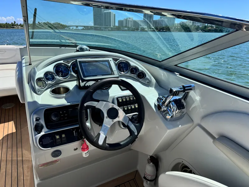 Slide: The Image of 2008 Crownline 300 LS boat dashboard with steering wheel and controls, overlooking water and cityscape. - 24