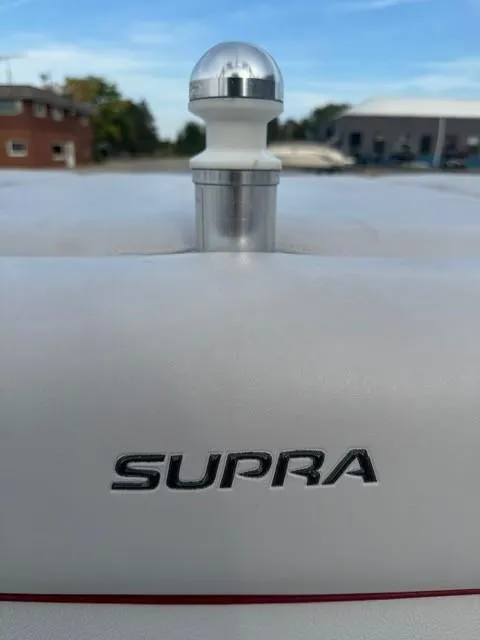 Slide: The Image of 2011 Supra 22v boat logo with chrome detail against a marina backdrop. - 20