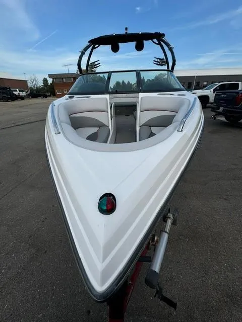 Slide: The Image of 2011 Supra 22v boat, white exterior, parked on a trailer in a lot. - 4