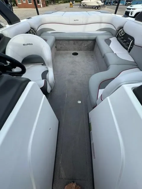 Slide: The Image of 2011 Supra 22v boat interior with white and gray seating, steering wheel, and spacious layout. - 6