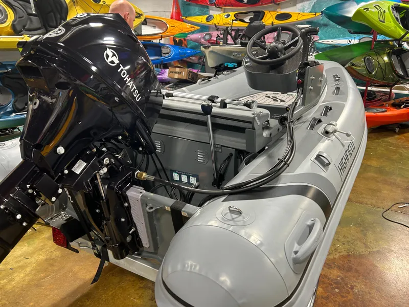 Slide: The Image of 2025 Highfield Classic 310 FCT inflatable boat with Tohatsu outboard motor in showroom. - 2