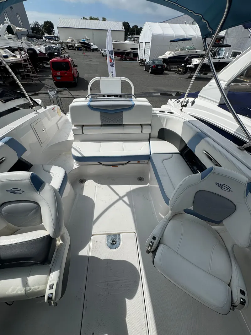Slide: The Image of 2022 Chaparral 267 SSX OB boat interior with white seating and canopy in a marina setting. - 19