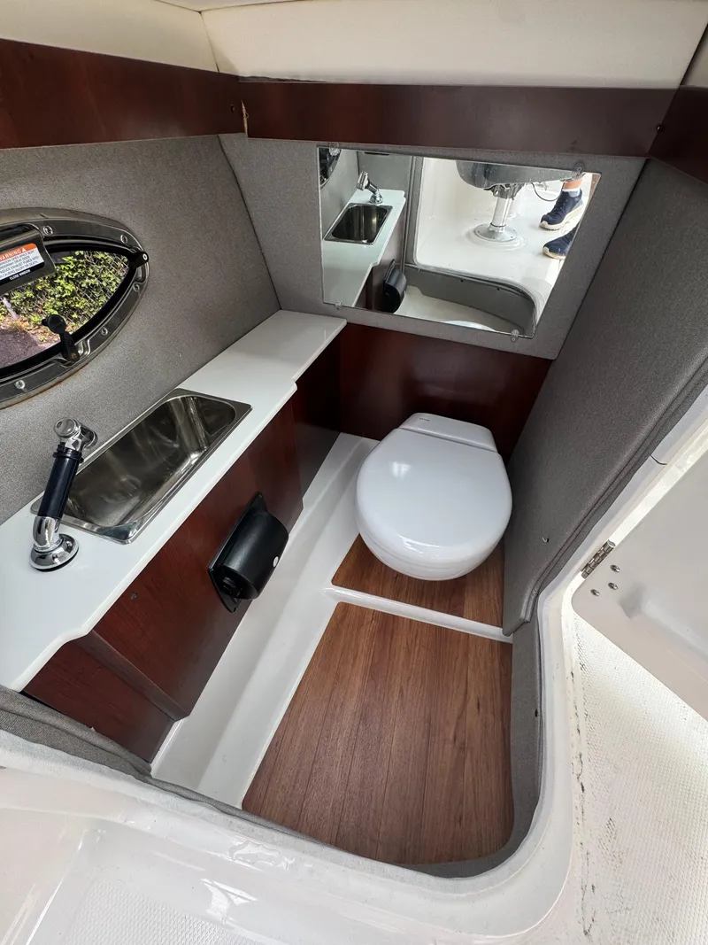 Slide: The Image of 2022 Chaparral 267 SSX OB boat bathroom with sink, toilet, and mirror. - 21
