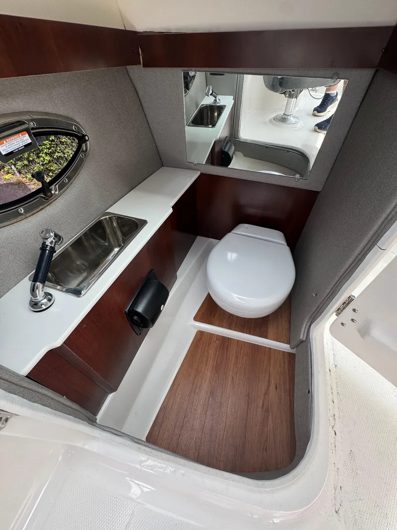 Slide: The Image of 2022 Chaparral 267 SSX OB boat bathroom with sink, toilet, and mirror. - 22