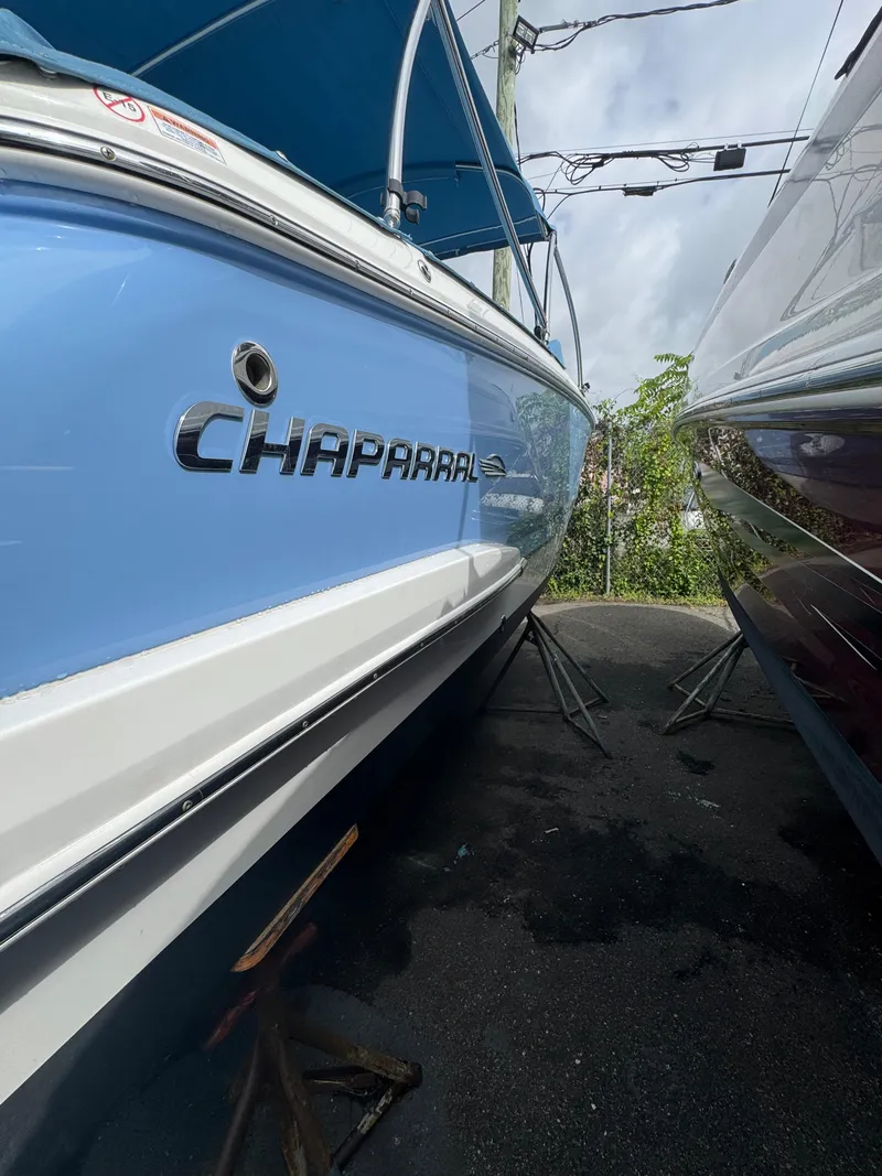 Slide: The Image of 2022 Chaparral 267 SSX OB boat in blue and white, parked outdoors. - 4