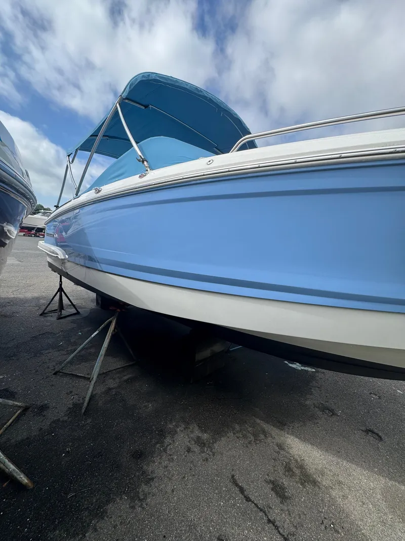 Slide: The Image of 2022 Chaparral 267 SSX OB boat with blue hull and canopy, parked on a stand. - 5