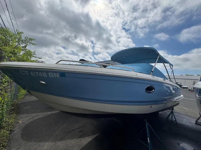 Slide: The Image of 2022 Chaparral 267 SSX OB boat with blue hull, parked outdoors under cloudy sky. - 6