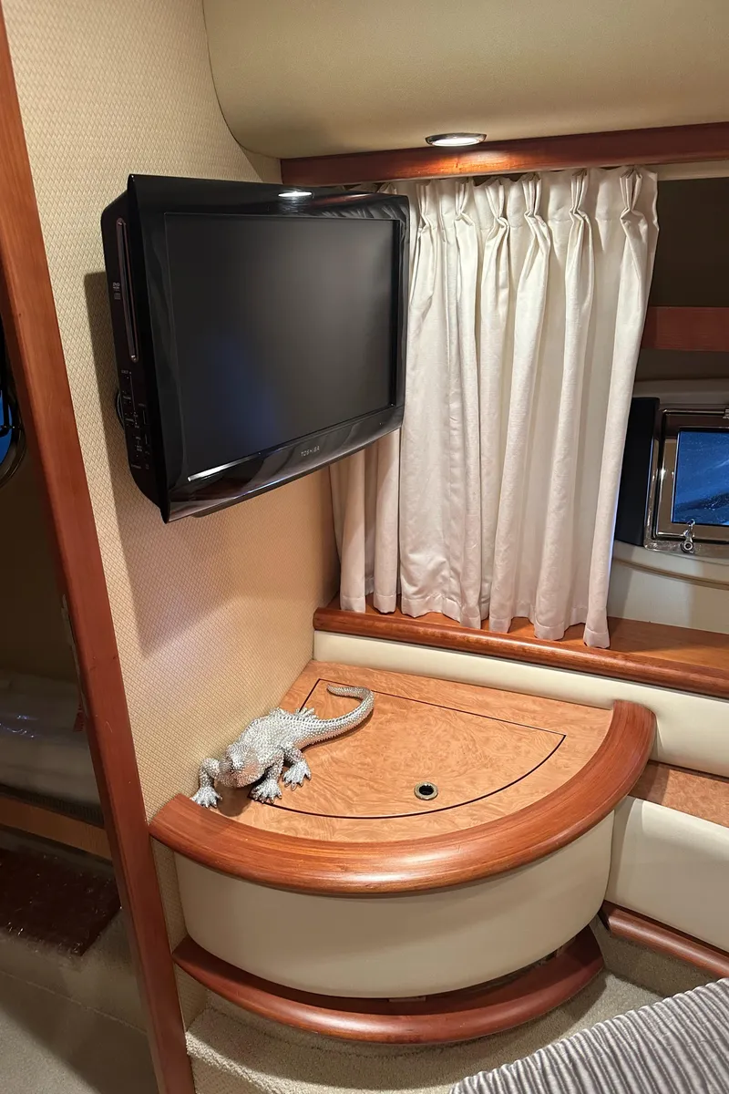 Slide: The Image of 2011 Azimut 62E yacht interior with TV, wooden cabinet, and window curtains. - 32