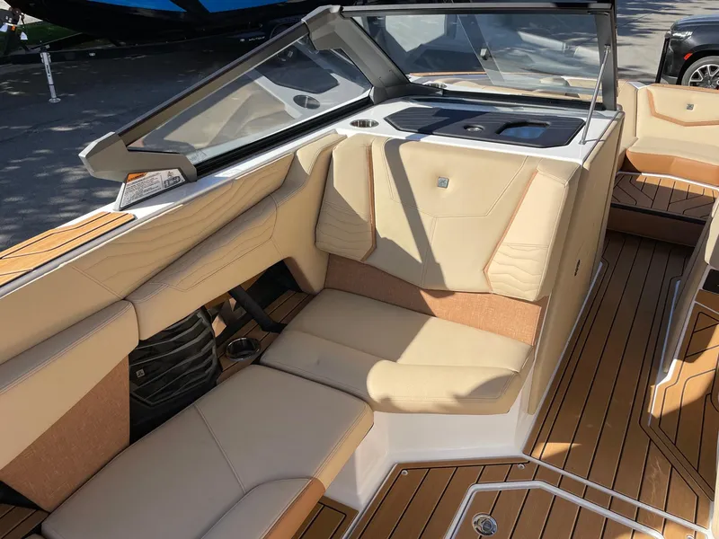 Slide: The Image of 2025 Nautique Super Air Nautique G23 interior with beige seating and teak flooring. - 10