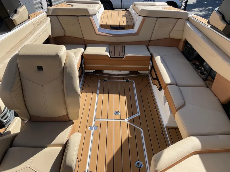 Slide: The Image of 2025 Nautique Super Air Nautique G23 interior with luxurious tan seating and teak flooring. - 12