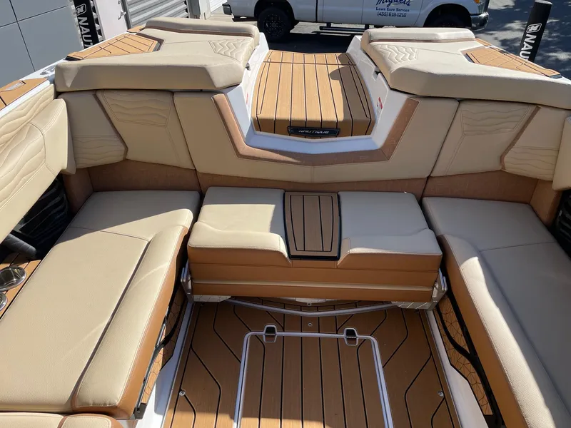 Slide: The Image of 2025 Nautique Super Air Nautique G23 boat interior with tan seating and teak flooring. - 8