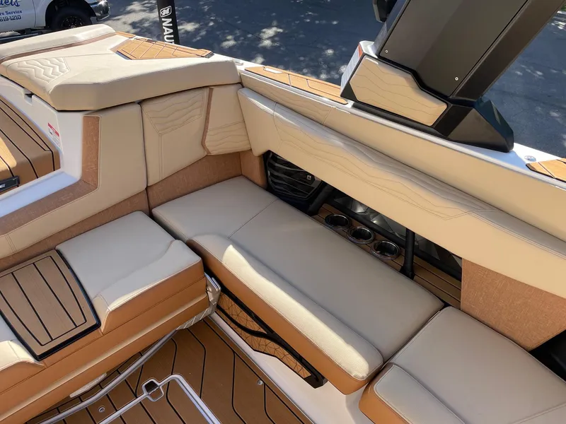 Slide: The Image of 2025 Nautique Super Air Nautique G23 interior with beige seating and cup holders. - 9