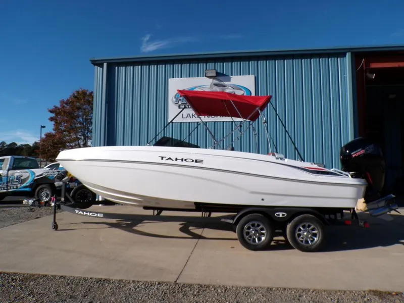 The Image of 2025 Tahoe T21 boat with red canopy on trailer, parked outside blue building. - 1