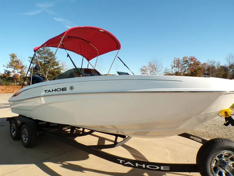 Slide: The Image of 2025 Tahoe T21 boat with red canopy on trailer, parked outdoors. - 3