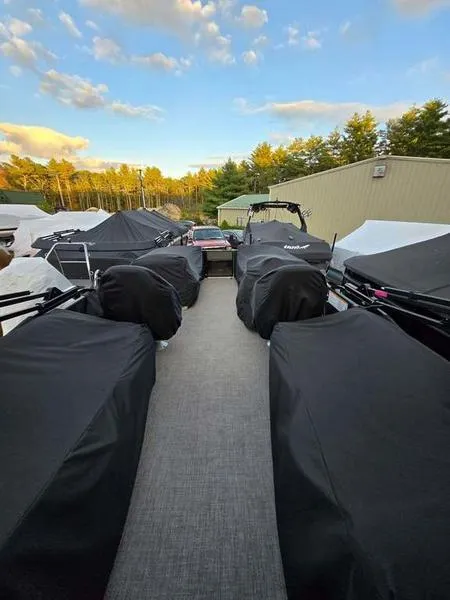 Slide: The Image of 2022 Barletta C20QC pontoon boat covered, parked outdoors under a blue sky. - 9