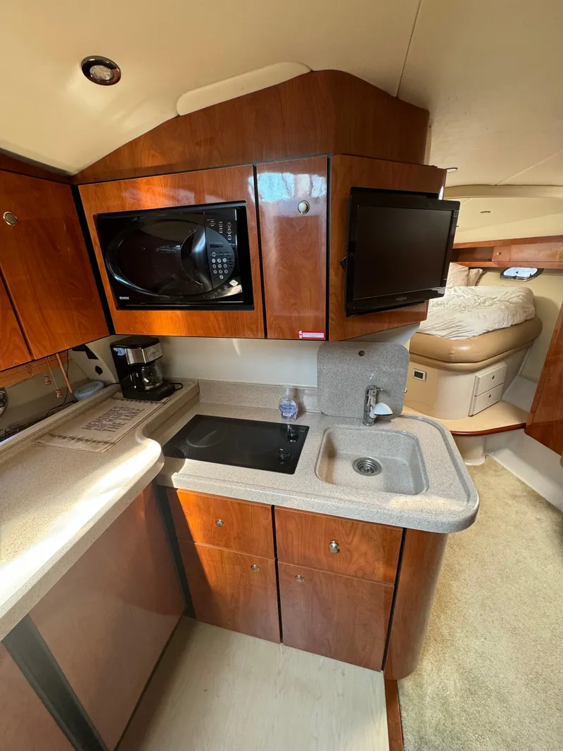Slide: The Image of 2005 Four Winns 378 Vista yacht interior with kitchenette, microwave, sink, and cozy sleeping area. - 11