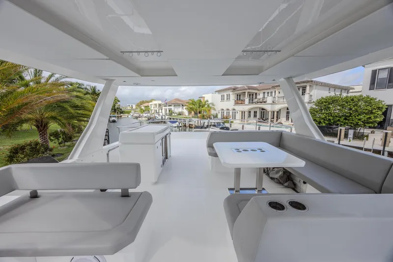 Slide: The Image of 2024 Leopard 53 Powercat yacht interior with modern seating and table, docked near waterfront homes. - 5