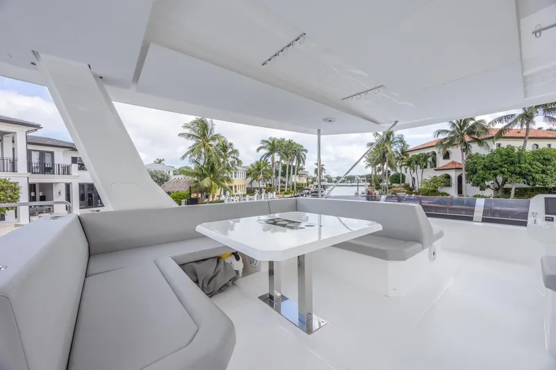 Slide: The Image of 2024 Leopard 53 Powercat yacht with spacious outdoor seating and table, surrounded by palm trees. - 6