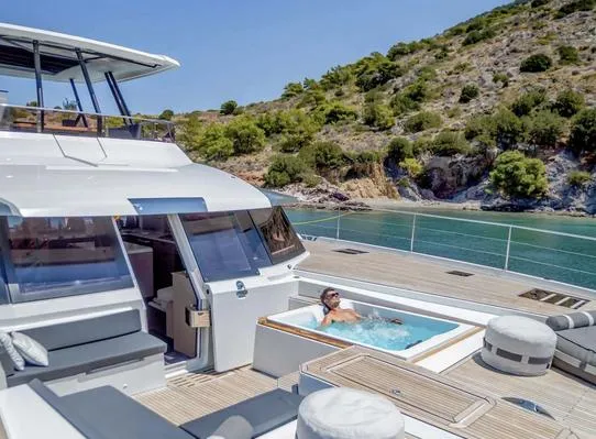 Slide: The Image of 2025 Fountaine Pajot Power 67 yacht with jacuzzi, scenic coastal backdrop. - 11