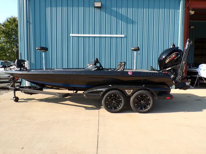 The Image of 2025 Skeeter FXR20L black fishing boat parked outside a blue building. - 1