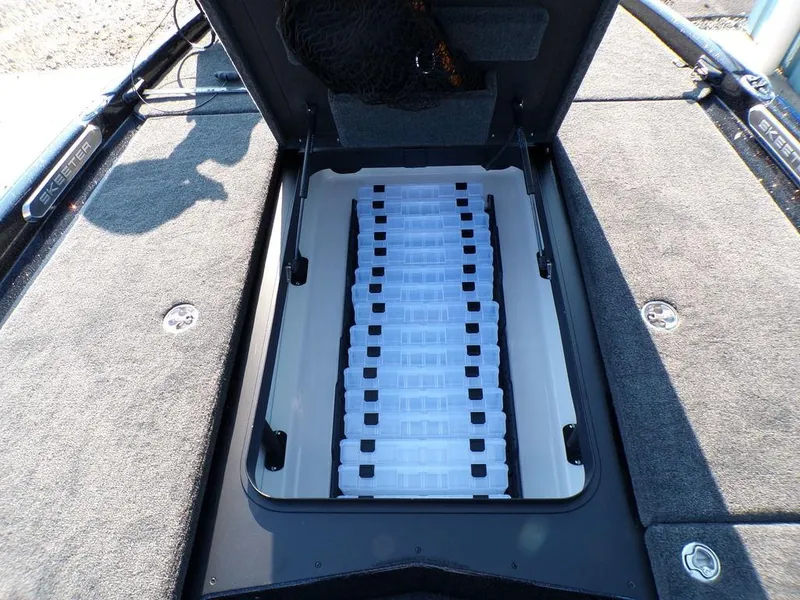 Slide: The Image of 2025 Skeeter FXR20L boat storage compartment with organized tackle boxes. - 19