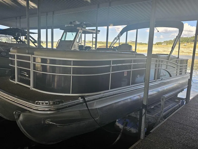 Slide: The Image of 2012 Bennington 25 RCW pontoon boat docked under a covered marina. - 0