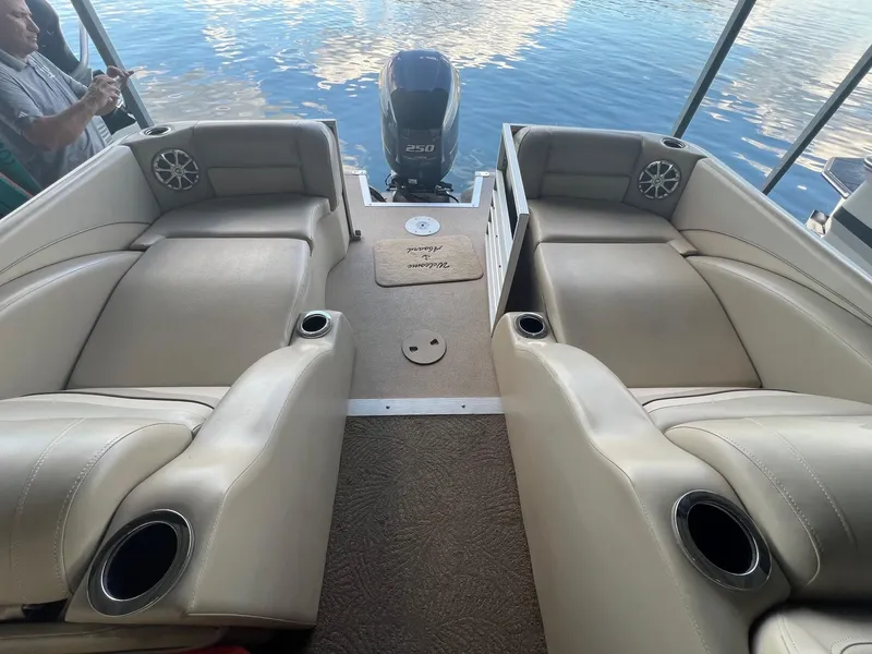 Slide: The Image of 2012 Bennington 25 RCW boat interior with beige seating and cup holders on a calm lake. - 13
