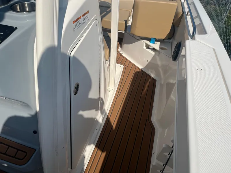 Slide: The Image of 2025 Bayliner Trophy T22CC boat interior with teak flooring and beige seating. - 15