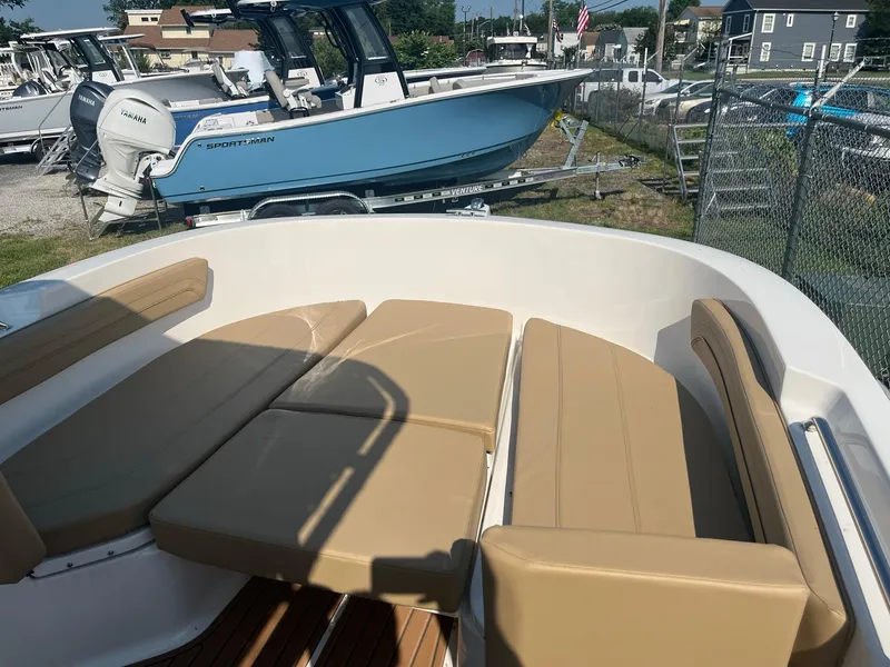 Slide: The Image of 2025 Bayliner Trophy T22CC boat interior with tan seating, docked near other boats. - 18