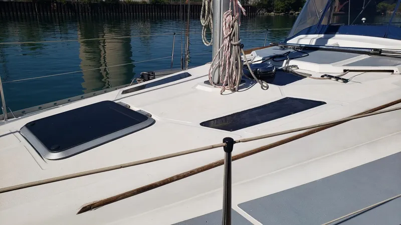 Slide: The Image of 1989 Hunter Legend 37 sailboat deck with hatches and rigging, docked by calm water. - 11