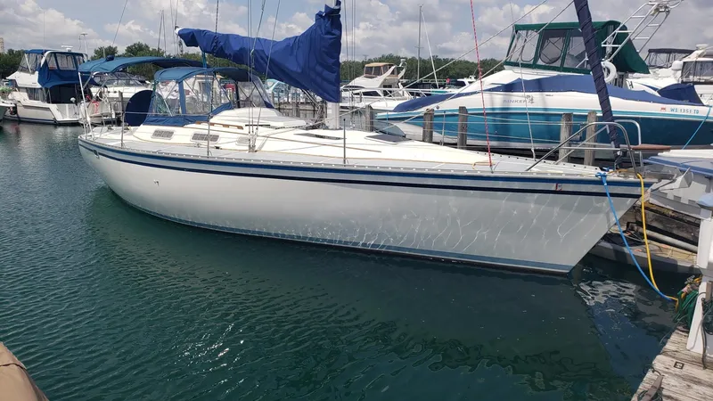 Slide: The Image of 1989 Hunter Legend 37 sailboat docked in a marina, featuring blue accents and a covered cockpit. - 2