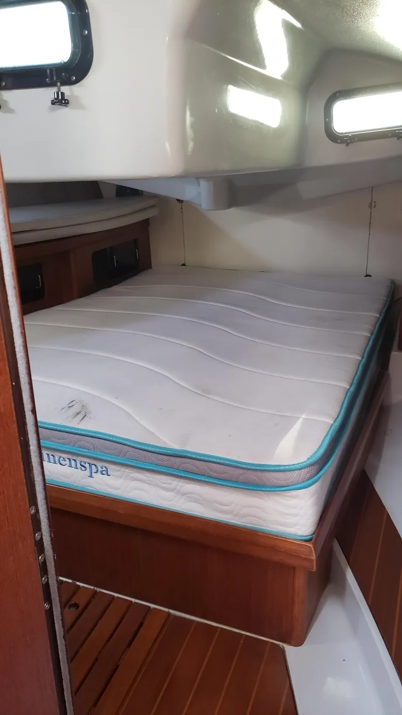 Slide: The Image of 1989 Hunter Legend 37 interior cabin with mattress, wooden finish, and porthole windows. - 27