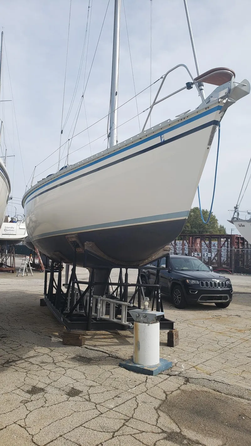 Slide: The Image of 1989 Hunter Legend 37 sailboat on dry dock, with a car nearby. - 33