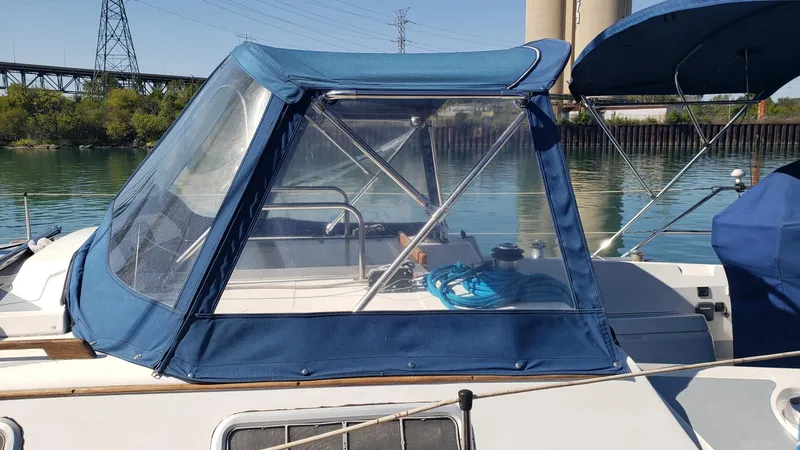 Slide: The Image of 1989 Hunter Legend 37 sailboat with blue canopy docked by a calm river. - 7