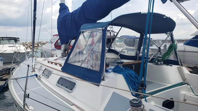Slide: The Image of 1989 Hunter Legend 37 sailboat docked at marina, featuring blue canopy and rigging. - 9